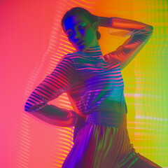 Young woman dancing on colorful glowing background