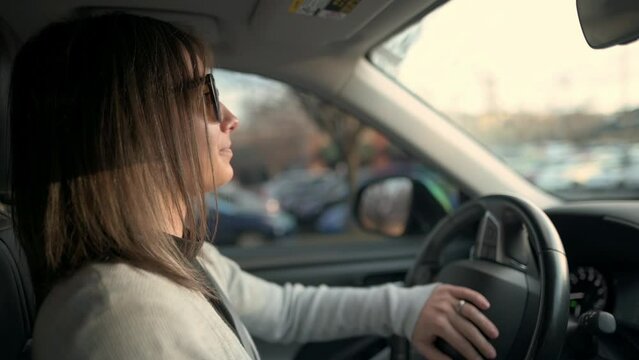 A woman appears tense and focused as she navigates her car through congested city traffic, depicting a common urban commuting challenge.