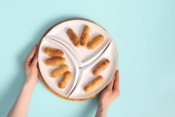 Woman's Hands Holding a Plate of Sweet Delights for Tea: Top-Down View of Croissants, Sweet Rolls, or Twisted Cookies.