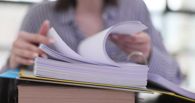 Woman quickly flips through stack of documents at workplace