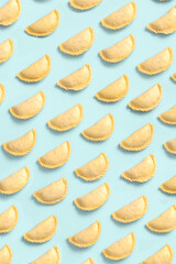 Top view on raw pies or samsa or samosas on blue background, frozen semi-finished products, bakery...