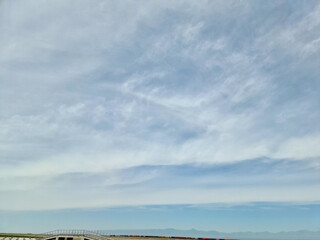 Obraz premium The sky is evenly filled with clouds stretching to the horizon, where a freight train is traveling.