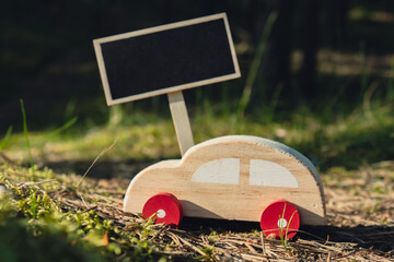 Empty blackboard with copy space Wooden toy car on greenery forest background. Eco-car concept World car free day electric vehicle environment automobile transportation electric vehicle. Hybrid