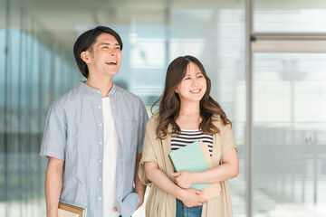 Fototapeta premium 教科書・ノートを持つ学生・大学生の男女（キャンパスライフ・恋人・カップル） 