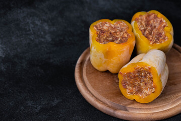 Frozen stuffed peppers filled with meat and rice, on dark black background, semi-finished, ready for cooking. Convenience and homemade frozen healthy meals.