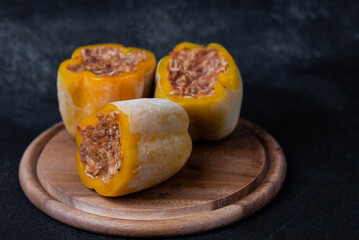 Frozen stuffed peppers filled with meat and rice, on dark black background, semi-finished, ready for cooking. Convenience and homemade frozen healthy meals.