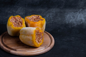 Frozen stuffed peppers filled with meat and rice, on dark black background, semi-finished, ready for cooking. Convenience and homemade frozen healthy meals.