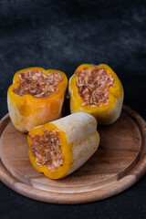 Frozen stuffed peppers filled with meat and rice, on dark black background, semi-finished, ready for cooking. Convenience and homemade frozen healthy meals.