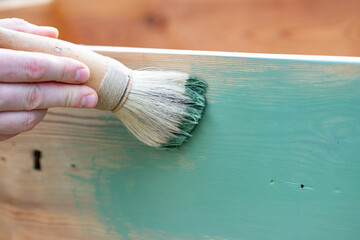 Man painting a wooden furniture outdoors, an eco-friendly re-use business.