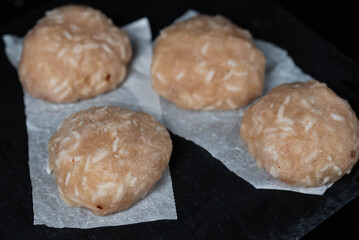 Frozen chicken meat cutlets on dark black background, semi-finished, ready for cooking. Convenience and homemade frozen healthy meals.