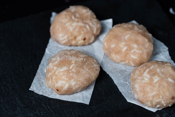 Frozen chicken meat cutlets on dark black background, semi-finished, ready for cooking. Convenience and homemade frozen healthy meals.