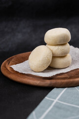 Frozen syrniki (cottage cheese pancakes) with vanilla flavor on dark black background, semi-finished, ready for cooking. Convenience and homemade frozen healthy meals.