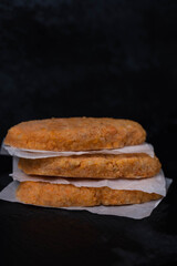 Frozen fish cutlets on dark black background, semi-finished, ready for cooking. Convenience and homemade frozen healthy meals.