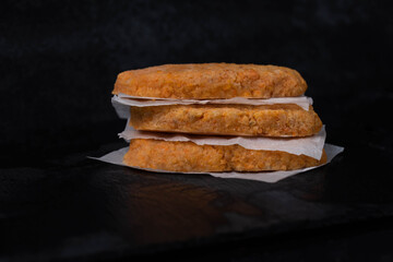 Frozen fish cutlets on dark black background, semi-finished, ready for cooking. Convenience and homemade frozen healthy meals.