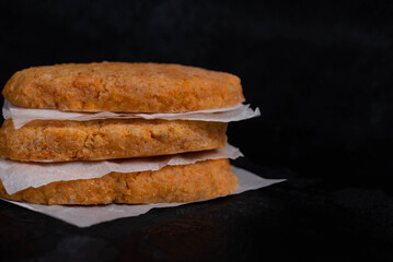 Frozen fish cutlets on dark black background, semi-finished, ready for cooking. Convenience and homemade frozen healthy meals.