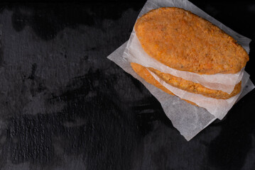 Frozen fish cutlets on dark black background, semi-finished, ready for cooking. Convenience and...