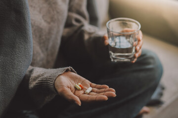 Upset woman frustrated by problem with work or relationships, sitting on couch, embracing knees, covered face in hand, feeling despair and anxiety, loneliness, having psychological trouble