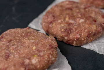 Frozen meat cutlets on dark black background, semi-finished, ready for cooking. Convenience and homemade frozen healthy meals.