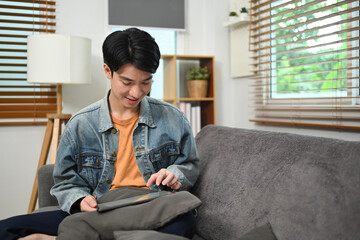 Young man doing online shopping or browsing internet on digital tablet at home