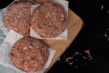 Frozen meat cutlets on dark black background, semi-finished, ready for cooking. Convenience and homemade frozen healthy meals.