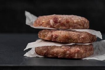 Frozen meat cutlets on dark black background, semi-finished, ready for cooking. Convenience and...