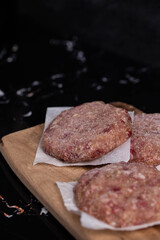 Frozen meat cutlets on dark black background, semi-finished, ready for cooking. Convenience and homemade frozen healthy meals.