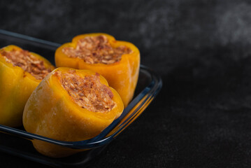 Frozen stuffed peppers filled with meat and rice, on dark black background, semi-finished, ready for cooking. Convenience and homemade frozen healthy meals.