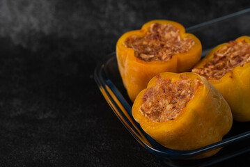 Frozen stuffed peppers filled with meat and rice, on dark black background, semi-finished, ready for cooking. Convenience and homemade frozen healthy meals.