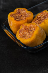 Frozen stuffed peppers filled with meat and rice, on dark black background, semi-finished, ready for cooking. Convenience and homemade frozen healthy meals.