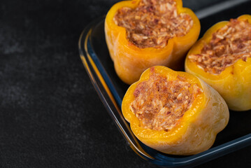 Frozen stuffed peppers filled with meat and rice, on dark black background, semi-finished, ready for cooking. Convenience and homemade frozen healthy meals.