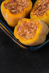 Frozen stuffed peppers filled with meat and rice, on dark black background, semi-finished, ready for cooking. Convenience and homemade frozen healthy meals.