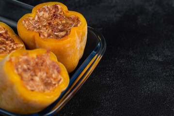 Frozen stuffed peppers filled with meat and rice, on dark black background, semi-finished, ready for cooking. Convenience and homemade frozen healthy meals.