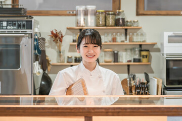 カフェ・居酒屋・飲食店の厨房で働く調理師のアジア人女性
