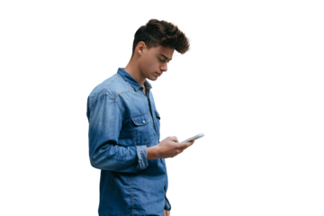 young man in a denim shirt checks his phone while standing against transparent background