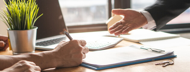 Close-up of hands of realtor explaining a lease contract to client on the table