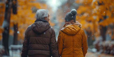 Back view of a senior retired couple walking along a path in park