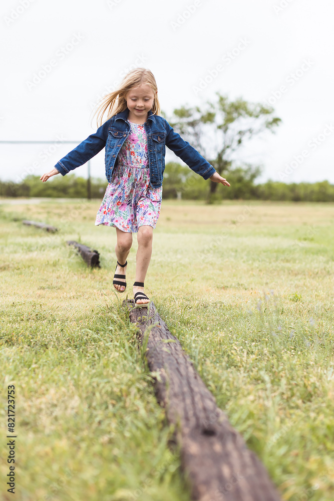 Wall mural Happy Girl In Dress Walking on Log on a Rainy Spring Day