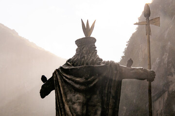 Crowned statue in Aguas Calientes, Peru, misty backdrop