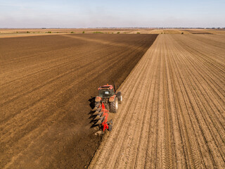 Aerial view of a tractor plowing rich farmland at the break of dawn
