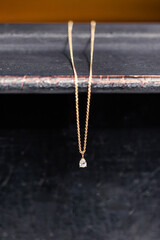 Gold necklace with a diamond pendant against a dark background