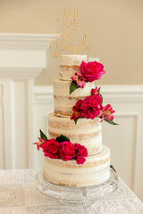 Four-tier semi-naked wedding cake with vibrant pink flowers