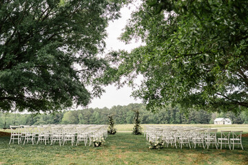 Fototapeta premium Outdoor wedding ceremony with white chairs and florals