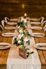 Rustic wedding reception table with candles and greenery