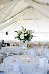 Wedding reception tent with chandeliers and white floral centerpieces