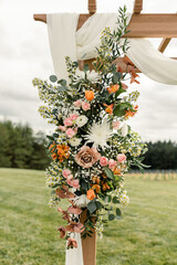 Floral arrangement on a wedding arch with roses and daisies