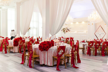 Wedding reception with red and gold decor and floral centerpieces