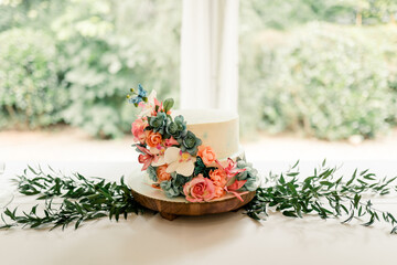 Elegant two-tiered wedding cake with floral decorations and greenery