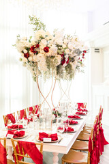 Wedding reception table with tall floral centerpieces and red decor