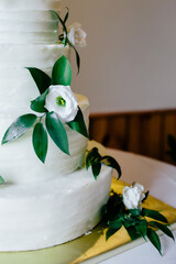 Elegant white wedding cake with green leaves and white flowers