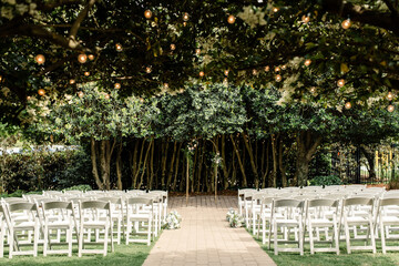 Outdoor wedding ceremony setup with white chairs and string lights